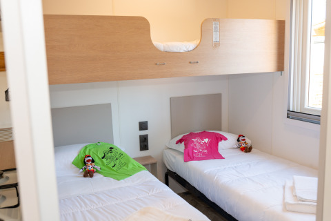 Habitación de cabaña en Cottage Next XL Mercure en Trasimeno Glamping Resort, Italia, con literas y camas gemelas.