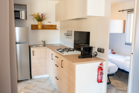 Cocina moderna y dormitorio en Cottage Next XL Mercure, Trasimeno Glamping Resort, Italia.