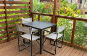 Terrazza all'aperto con tavolo nero e quattro sedie bianche al Cube Suite XL, Trasimeno Glamping Resort, Italia.