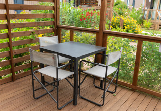 Buiten terras met zwarte tafel en vier witte stoelen bij Cube Suite XL, Trasimeno Glamping Resort, Italië.