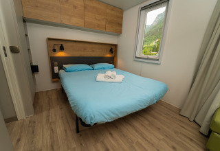 Moderne slaapkamer met tweepersoonsbed, blauw beddengoed en raam bij Cube Suite XL, Trasimeno Glamping Resort.