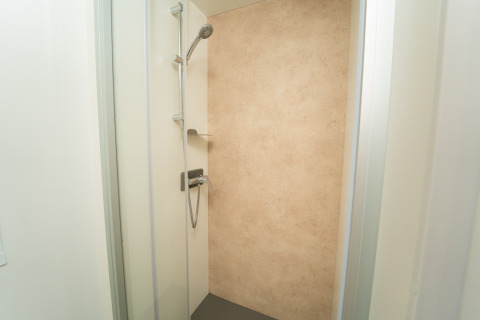 Moderne douche met beige wand in Cube Suite XL bij Trasimeno Glamping Resort, Italië, binnenaanzicht.