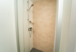 Moderne douche met beige wand in Cube Suite XL bij Trasimeno Glamping Resort, Italië, binnenaanzicht.