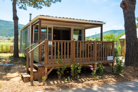 Vista exterior del alojamiento Cottage Classic Suite con porche de madera y paisaje natural al fondo.