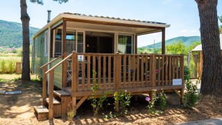 Vista esterna del lodge Cottage Classic Suite con veranda in legno, immerso nella natura verde.