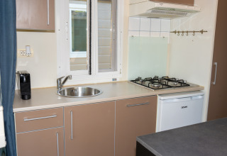Cocina compacta en la Suite Cottage Classic del Trasimeno Glamping Resort con fregadero y estufa de gas.