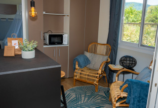 Sala de estar en la suite «Cottage Classic» en Trasimeno Glamping Resort con sillas de mimbre y grandes ventanales.