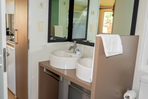 Baño moderno con doble lavabo y espejo en la suite Cottage Classic del Trasimeno Glamping Resort en Italia.