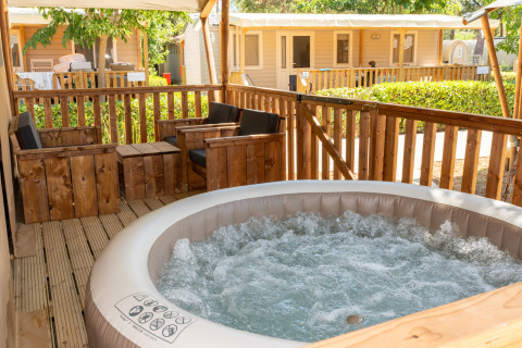 Buitenterras met jacuzzi en houten stoelen bij Safari Tent Comfort in Trasimeno Glamping Resort, Italië.