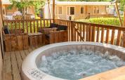 Terrazza esterna con vasca idromassaggio e sedie di legno al Safari Tent Comfort, Trasimeno Glamping Resort, Italia.