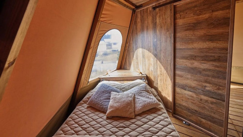Interieur van Tipi Lodge, Trasimeno Glamping Resort, Italië, met comfortabel bed en houten muren.