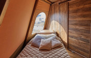 Interieur van Tipi Lodge, Trasimeno Glamping Resort, Italië, met comfortabel bed en houten muren.