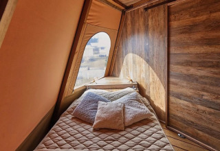 Interieur van Tipi Lodge, Trasimeno Glamping Resort, Italië, met comfortabel bed en houten muren.