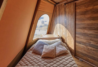 Interieur van Tipi Lodge, Trasimeno Glamping Resort, Italië, met comfortabel bed en houten muren.