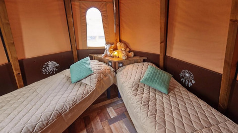 Interieur van de Tipi Lodge bij Trasimeno Glamping Resort in Italië, met twee eenpersoonsbedden en gezellige decoratie.
