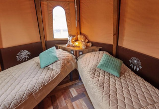 Interieur van de Tipi Lodge bij Trasimeno Glamping Resort in Italië, met twee eenpersoonsbedden en gezellige decoratie.