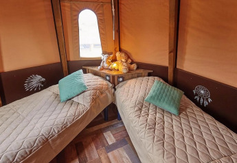 Interieur van de Tipi Lodge bij Trasimeno Glamping Resort in Italië, met twee eenpersoonsbedden en gezellige decoratie.