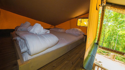 Binnenaanzicht van safaritent Spotty Lodge Ranger met comfortabel bed in Trasimeno Glamping Resort, Italië.