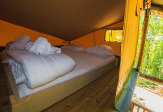 Binnenaanzicht van safaritent Spotty Lodge Ranger met comfortabel bed in Trasimeno Glamping Resort, Italië.