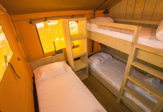 Binnenzicht van een safaritent met stapelbedden en een eenpersoonsbed in Spotty Lodge Ranger, Trasimeno Glamping Resort, Italië.