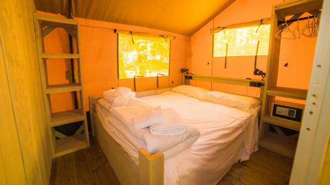 Gezellige slaapkamer in een safaritent met tweepersoonsbed bij Spotty Lodge, Trasimeno Glamping Resort, Italië.