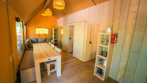 Binnenzicht van de Spotty Lodge Ranger safaritent bij Trasimeno Glamping Resort met houten meubels.