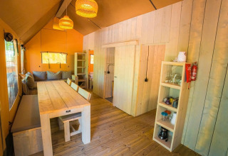 Binnenzicht van de Spotty Lodge Ranger safaritent bij Trasimeno Glamping Resort met houten meubels.