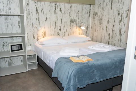 Dormitorio moderno en Cottage Next XL 4 All, Trasimeno Glamping Resort, con cama doble y libro abierto.