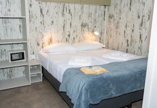 Dormitorio moderno en Cottage Next XL 4 All, Trasimeno Glamping Resort, con cama doble y libro abierto.