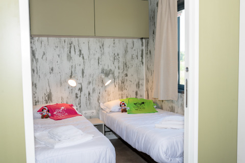Dormitorio con dos camas individuales y decoración moderna en Cottage Next XL 4 All, Trasimeno Glamping Resort.