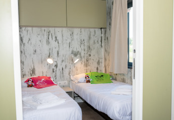 Dormitorio con dos camas individuales y decoración moderna en Cottage Next XL 4 All, Trasimeno Glamping Resort.