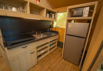 Espace cuisine dans une tente safari au Trasimeno Glamping Resort en Italie, avec évier, réfrigérateur et micro-ondes.