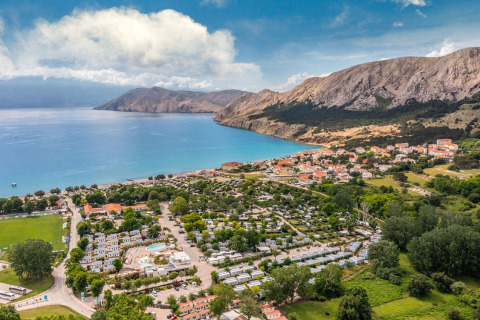 Aerial view of Campsite Baška holiday park with blue sea, mountains, and a village in Primorje-Gorski Kotar, Croatia.