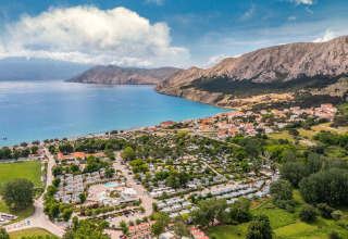 Aerial view of Campsite Baška holiday park with blue sea, mountains, and a village in Primorje-Gorski Kotar, Croatia.