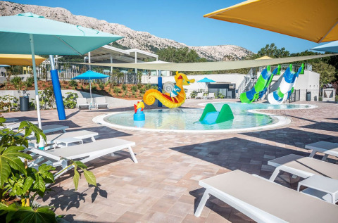 Piscina per bambini con scivoli, fontana a cavalluccio e lettini al Campeggio Baška in Croazia.