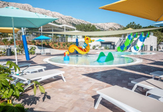 Colorful kids’ pool with slides, sea horse fountain, and sun loungers at Campsite Baška in Croatia.
