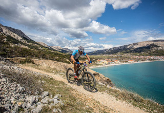 Un ciclista percorre un sentiero costiero con vista panoramica su Baška e il mare azzurro in Croazia.