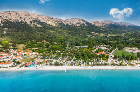 Vista aerea del campeggio Baška in Croazia con spiaggia, mare cristallino e montagne sullo sfondo.