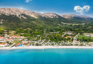 Aerial view of Campsite Baška in Croatia featuring a beach, clear blue sea, and mountains nearby.