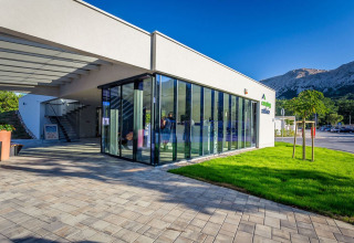 Ingresso moderno con vetrate e prato verde al Campeggio Baška, Primorje-Gorski Kotar, Croazia, vista montagne.