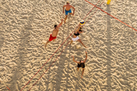 Vista aerea di quattro persone che giocano a beach volley sulla sabbia vicino a Baška, Croazia, soleggiata.