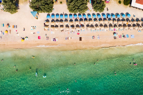 Vista aerea della spiaggia con ombrelloni e bagnanti al Campeggio Baška, Primorje-Gorski Kotar, Croazia.