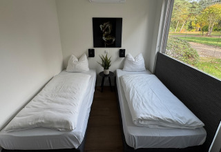 Two single beds in a modern room at Forest Lodge, Holiday Park BreeBronne, Netherlands, with garden view.