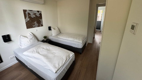 Kamer met twee enkele bedden in Forest Lodge bij Holiday Park BreeBronne, Nederland, vanuit de deur gezien.