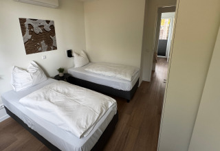 Værelse med to enkeltsenge i Forest Lodge på Holiday Park BreeBronne, Nederlandene, set fra døren.