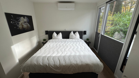 Bright bedroom at Forest Lodge in Holiday Park BreeBronne, Netherlands, with large windows facing greenery outside.