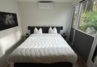 Bright bedroom at Forest Lodge in Holiday Park BreeBronne, Netherlands, with large windows facing greenery outside.