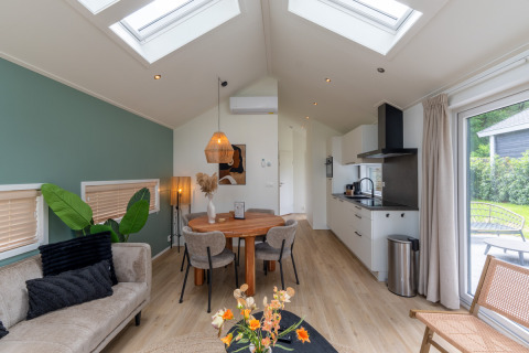 Modern interior of Wellness Cottage with skylights, dining table and kitchen at De Thijmse Berg, Netherlands.