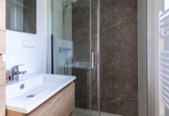 Baño moderno de cabaña con lavabo de madera, cabina de ducha de cristal y pared de mármol en De Thijmse Berg.