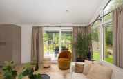 Lichte woonkamer bij Doornenburg Lodge Comfort, Veluwepark de Bosgraaf, Nederland, met grote ramen.